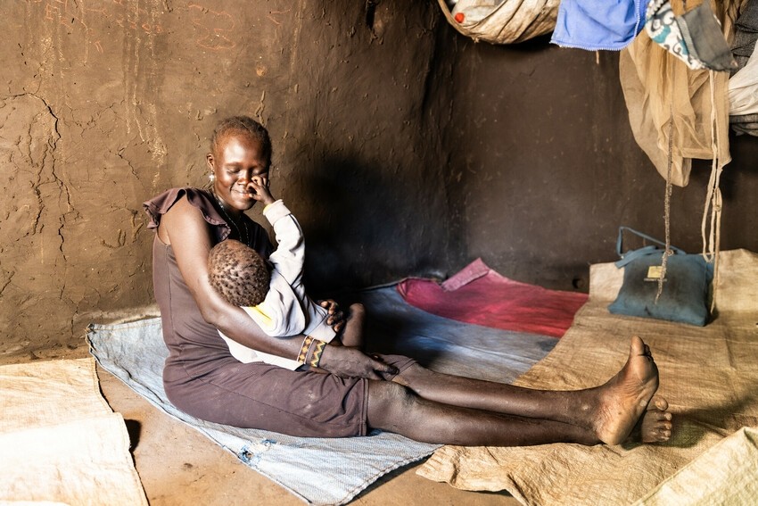 A woman sits on the floor and holds her daughter in her arms.