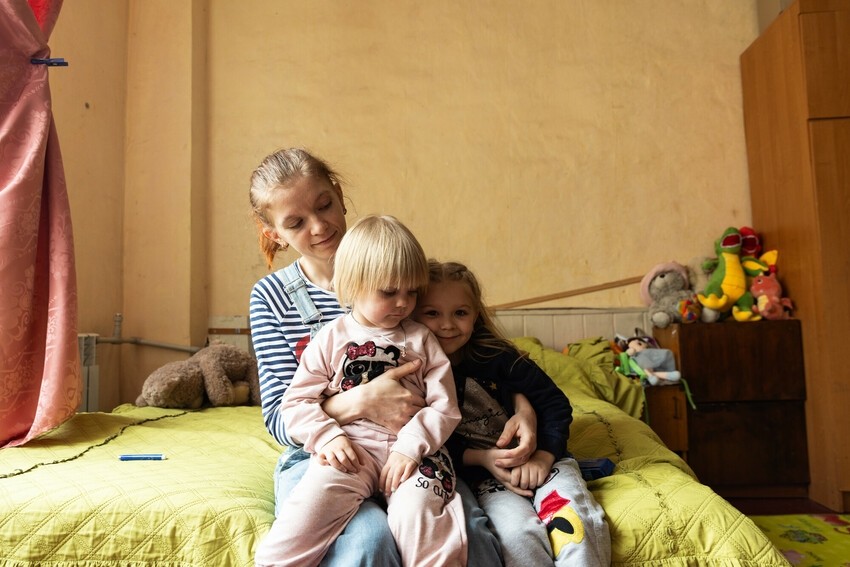 A woman cuddles her daughters at the Corus International-supported women’s center for displaced Ukrainians.
