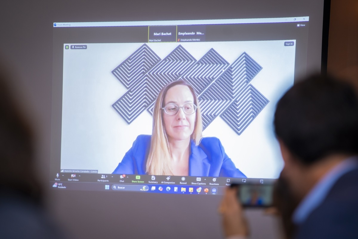 A woman on Zoom is projected on a screen at an event