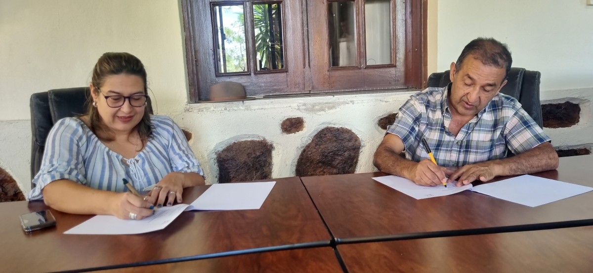 Two people sign documents at a desk