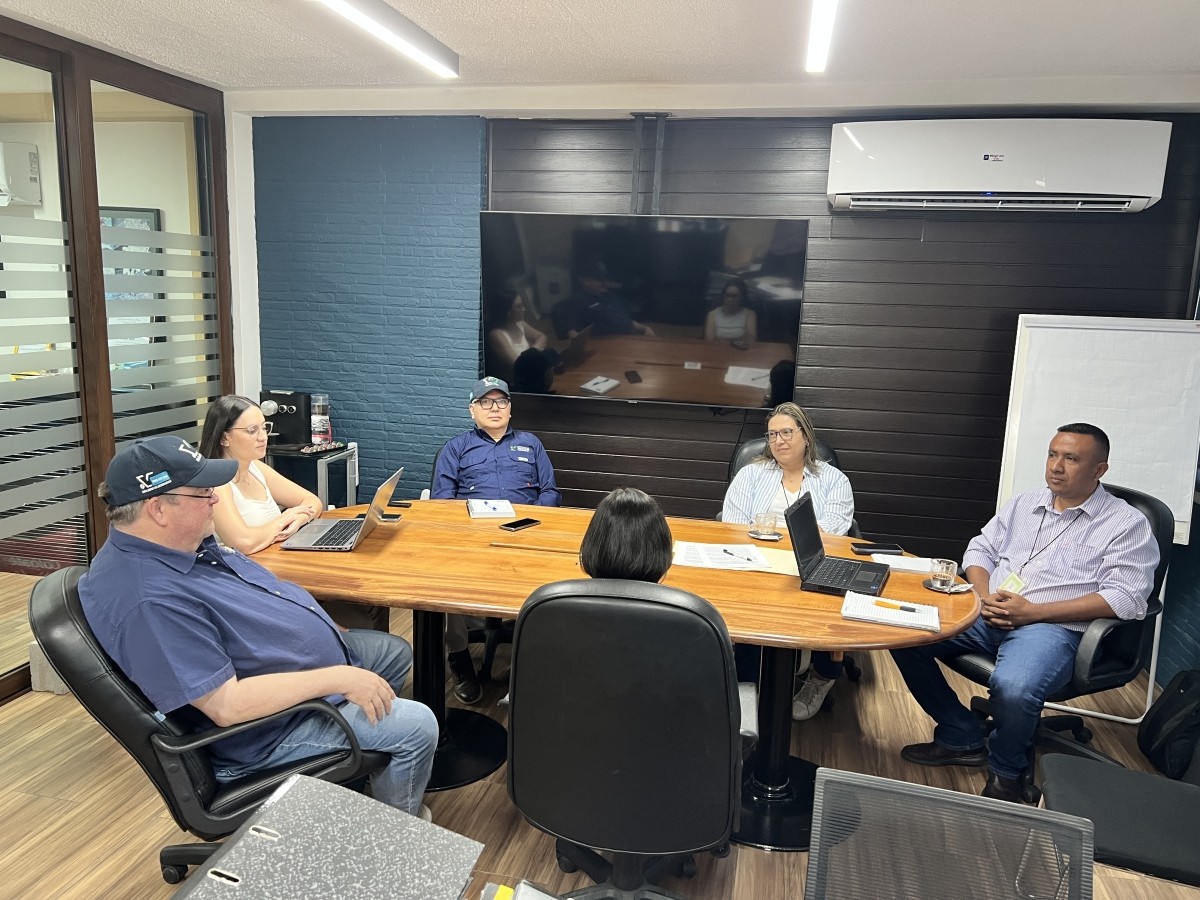 Six people sit around a desk in a business meeting